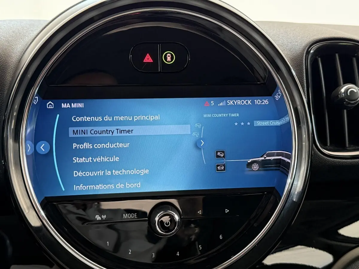 Vue rapprochée de l’écran tactile rond du tableau de bord d’une MINI Countryman gris clair, affichant le menu principal.