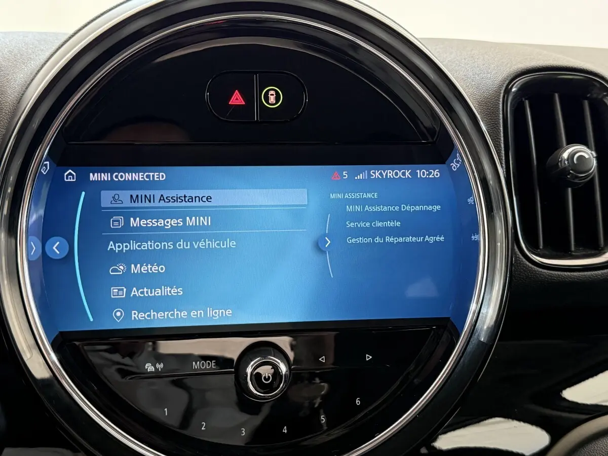 Écran tactile central rond affichant le menu MINI Connected, entouré de la console noire brillante du MINI Countryman gris clair.