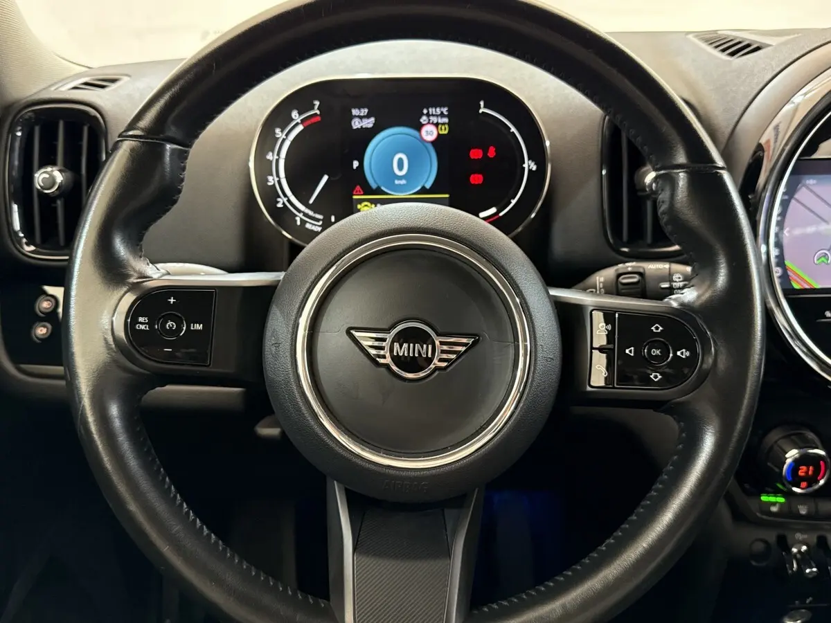 Vue rapprochée du volant cuir multifonctions noir de la MINI Countryman 2023 avec tableau de bord numérique allumé.