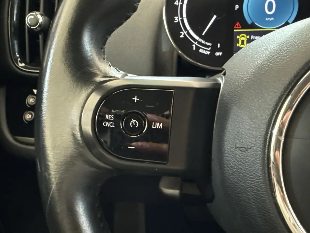 Gros plan sur le côté gauche du volant cuir noir d’un MINI Countryman 2023, avec commandes de régulateur de vitesse.