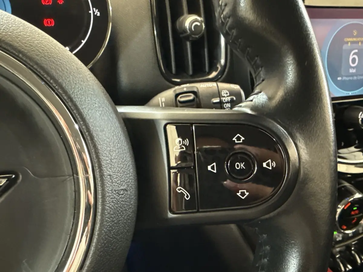 Gros plan sur le volant cuir noir multifonctions de la MINI Countryman gris clair, avec commandes intégrées visibles.
