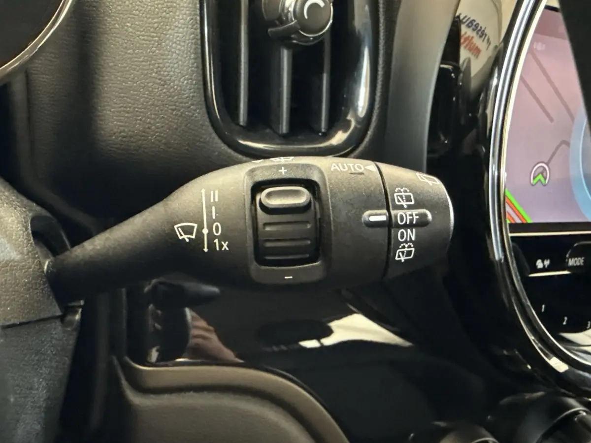 Gros plan sur la manette d’essuie-glace à gauche du volant dans l’habitacle noir d’une MINI Countryman gris clair.