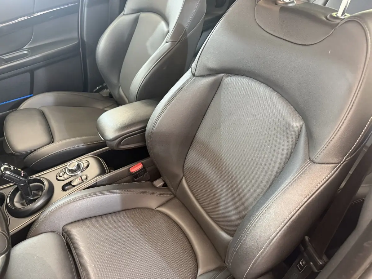 Gros plan sur les sièges avant en cuir noir et la console centrale d'une MINI Countryman gris clair, vue côté droit.