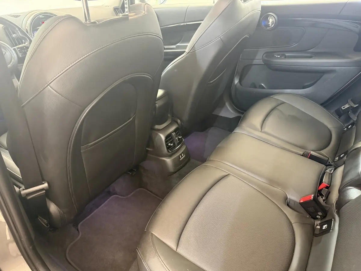 Vue intérieure arrière côté droit du MINI Countryman 2023, sièges en cuir noir et console centrale avec aérateurs.