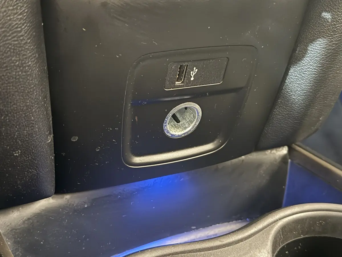 Prise USB et prise 12V en gros plan dans l’habitacle noir du MINI Countryman Cooper Essential 2023.