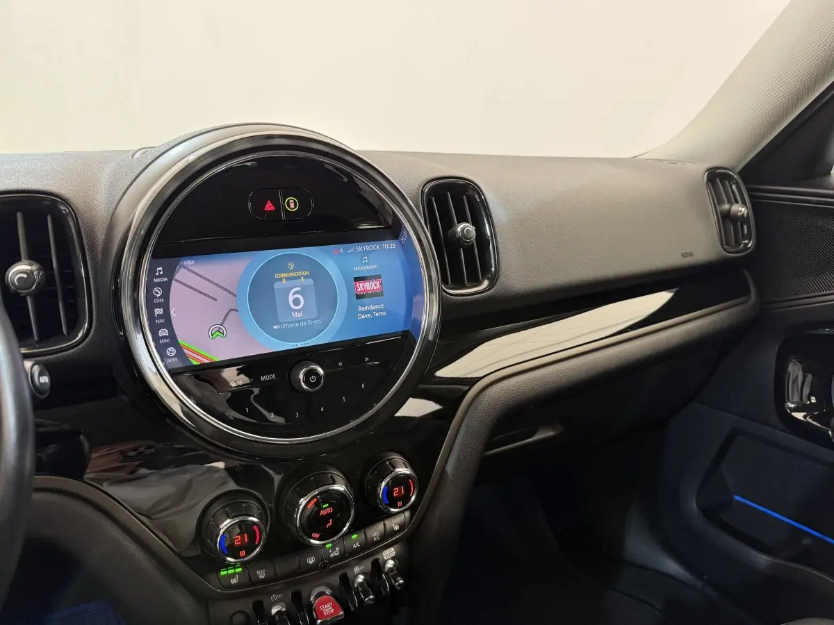Vue intérieure côté passager du tableau de bord noir brillant du MINI Countryman 2023 avec écran tactile rond central.