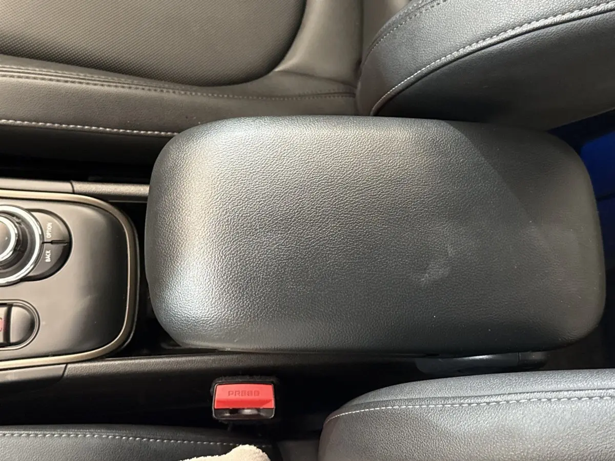 Vue rapprochée de l'accoudoir central en cuir noir et des commandes de la console centrale d'une MINI Countryman gris clair.