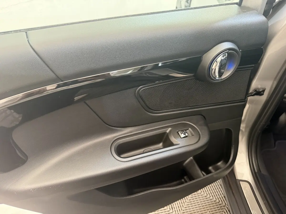 Vue rapprochée de la porte avant droite gris clair d’un MINI Countryman 2023 avec poignée chromée et commande de vitre.