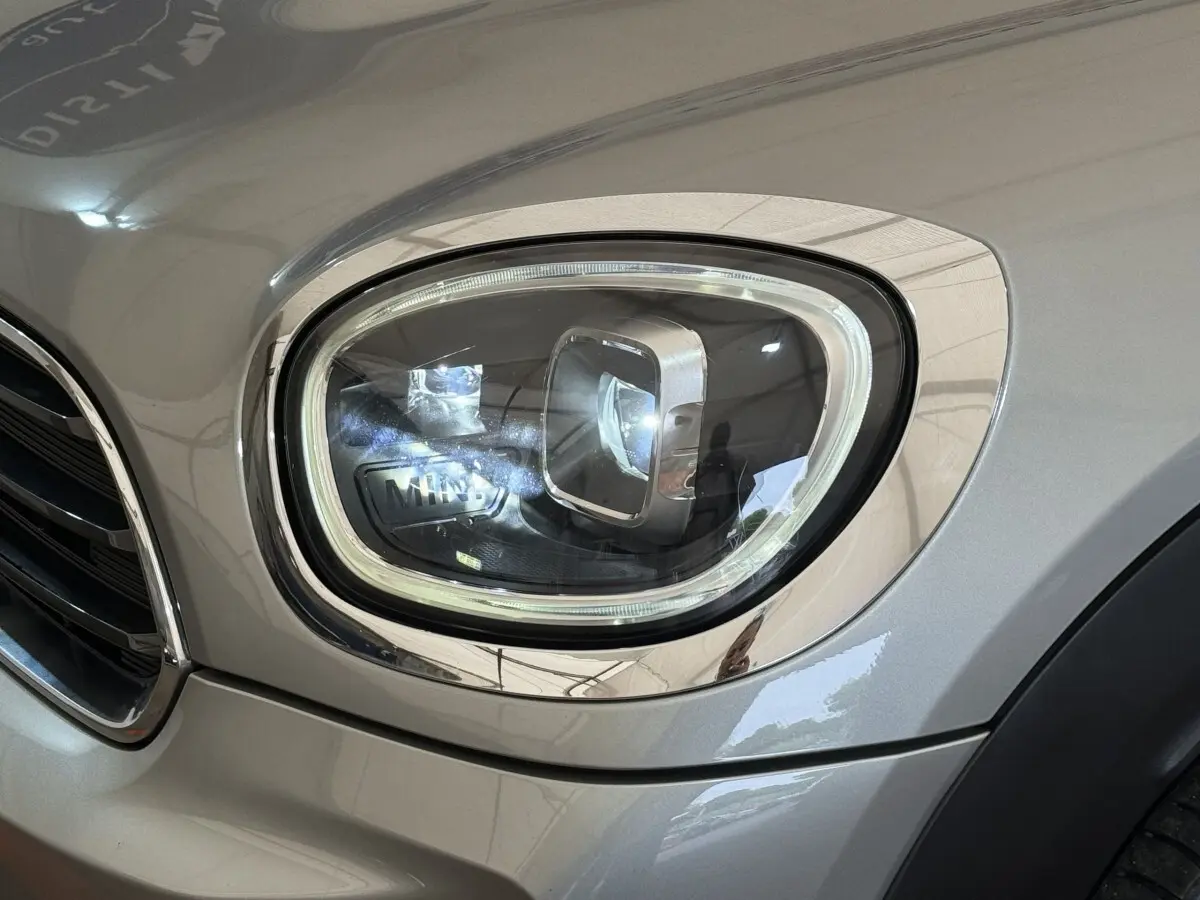 Gros plan sur le phare avant droit gris clair du MINI Countryman Cooper Essential 2023 avec détails chromés.