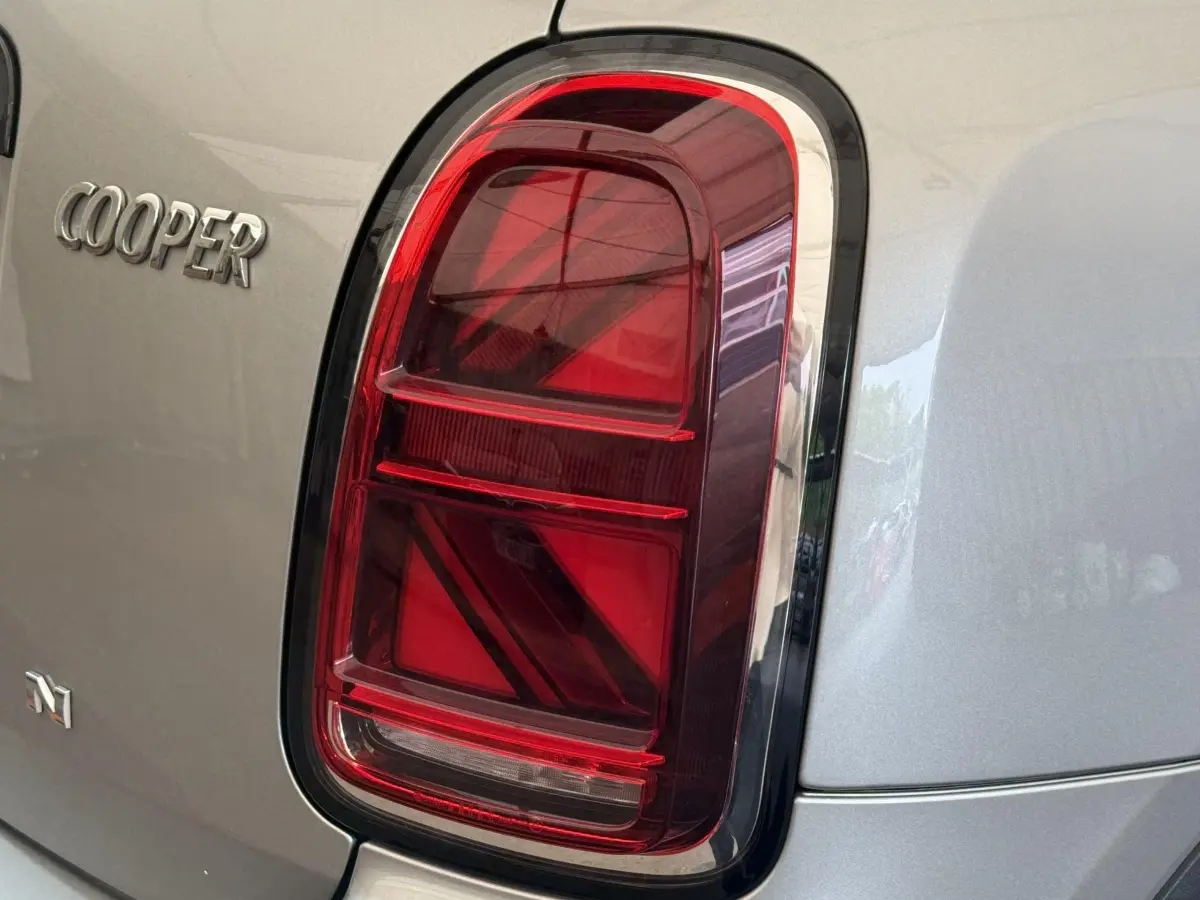 Gros plan sur le feu arrière droit rouge et le logo Cooper du MINI Countryman gris clair 2023.