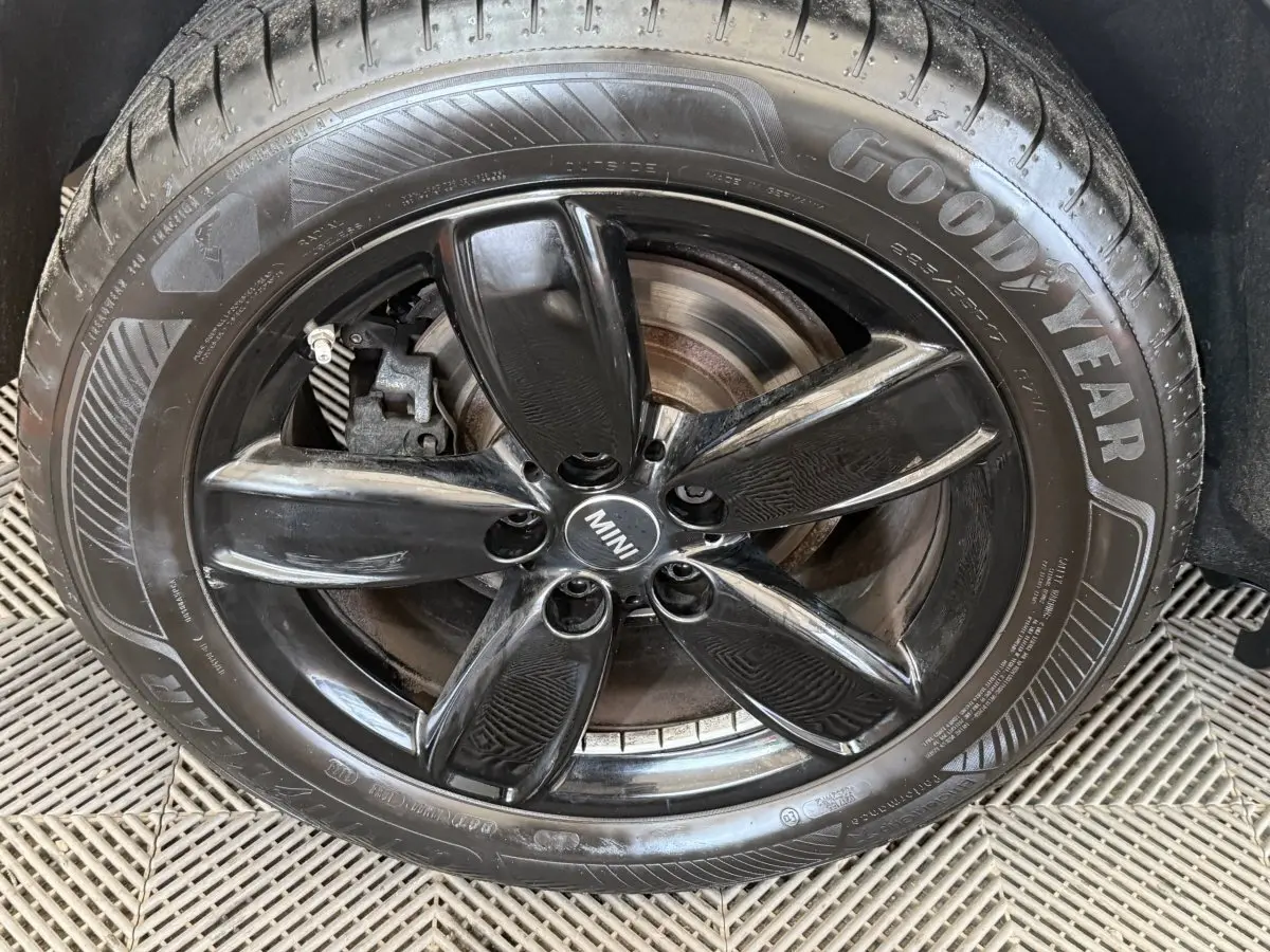 Gros plan sur la jante noire brillante à 5 branches du MINI Countryman gris clair, avec pneu Goodyear visible.