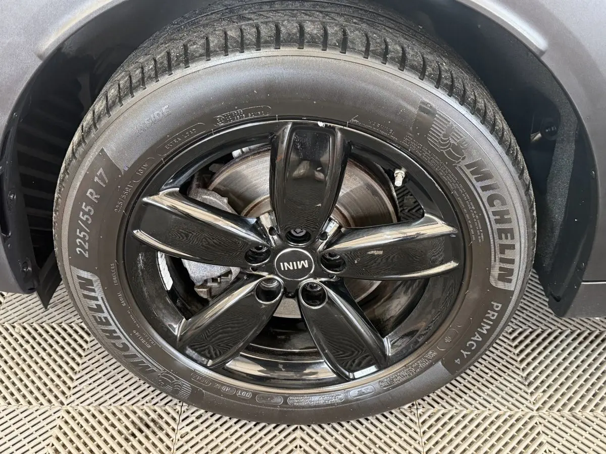 Gros plan sur la jante noire brillante et le pneu Michelin d'une MINI Countryman gris clair, côté roue avant.