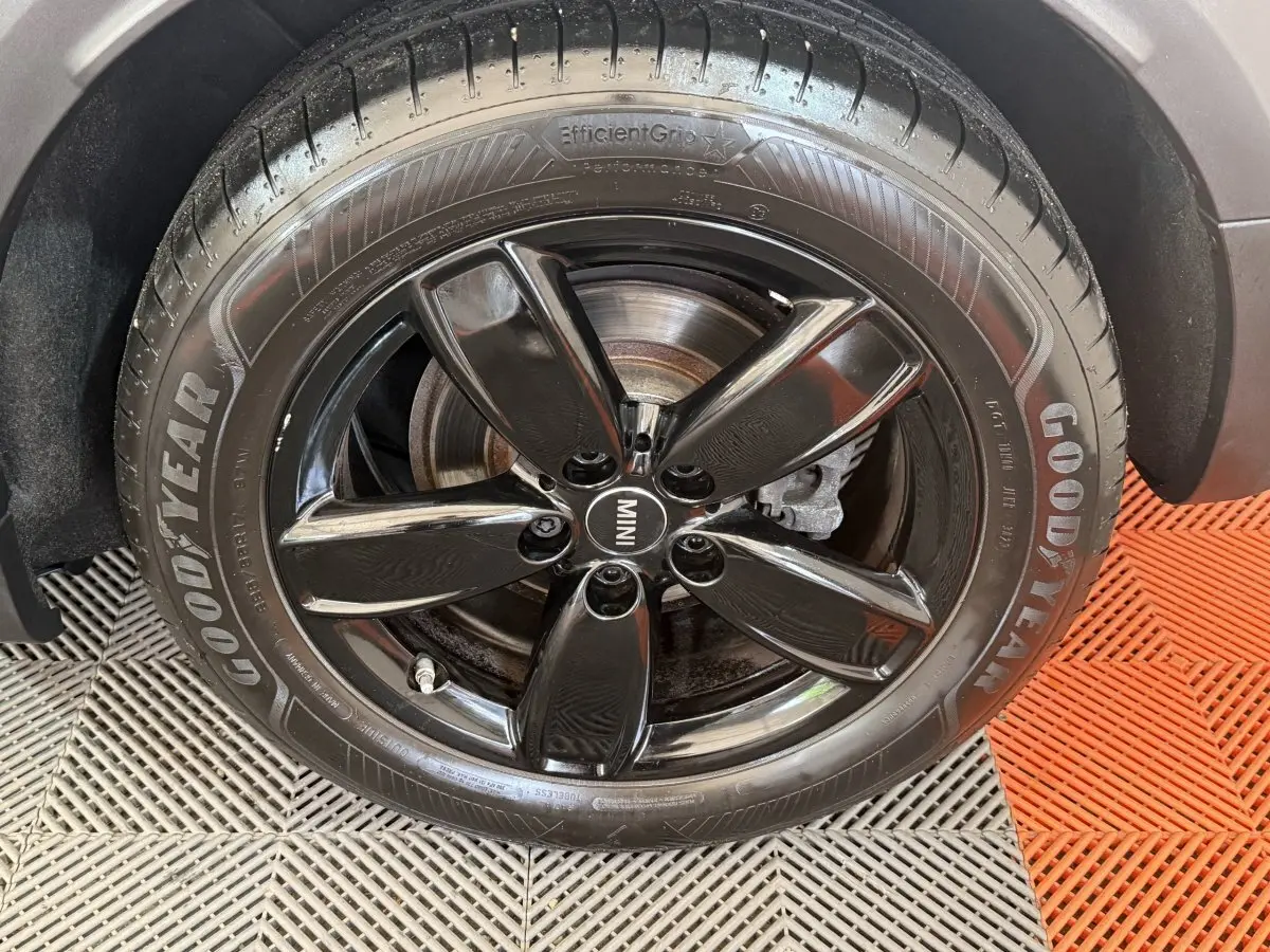 Gros plan sur la roue avant droite d’une MINI Countryman gris clair avec jante noire brillante et pneu Goodyear.