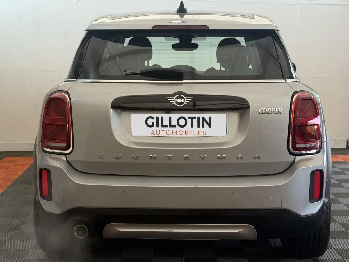 Vue arrière d'une MINI Countryman Cooper gris clair avec feux arrière rectangulaires et logo MINI centré.