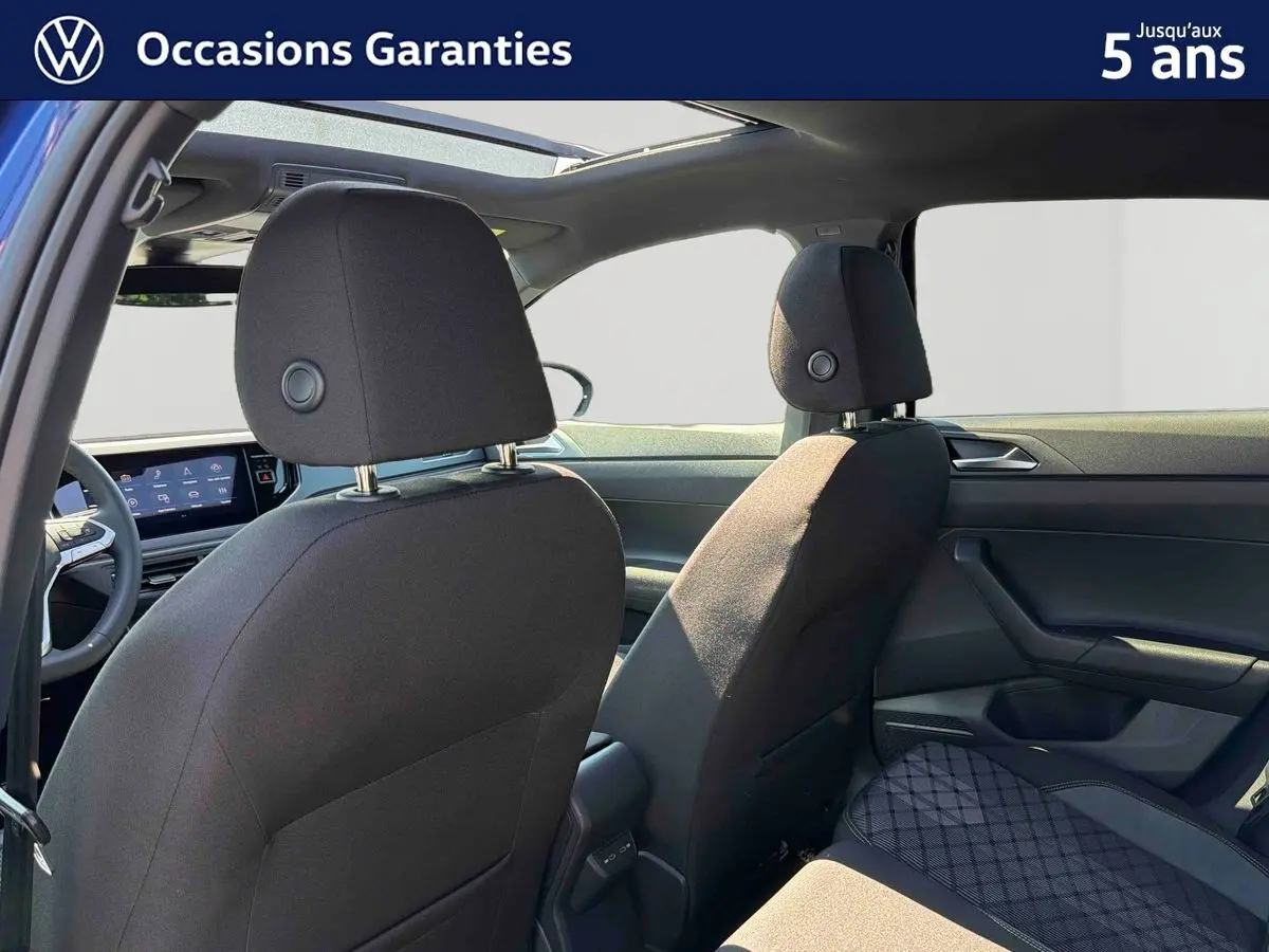 Vue intérieure arrière du Volkswagen Taigo bleu 2025 avec toit ouvrant électrique et sièges tissu noirs.