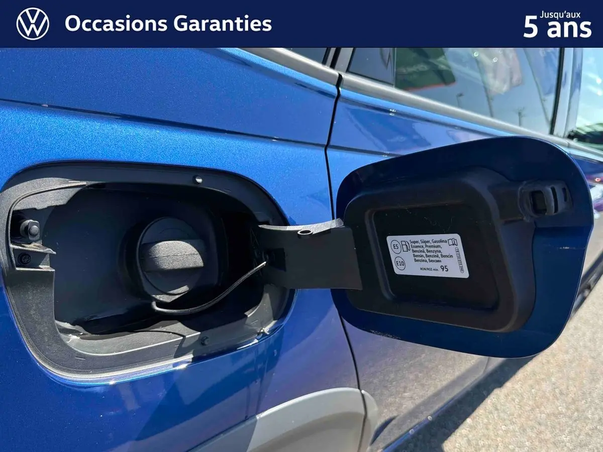 Détail de la trappe à carburant ouverte côté droit sur Volkswagen Taigo 2025 bleu métallisé.
