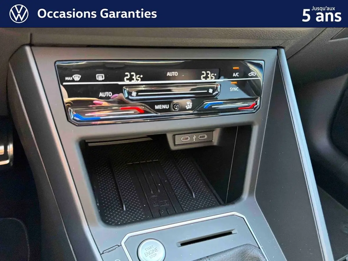Gros plan sur la console centrale noire du Volkswagen Taigo 2025, avec commandes climatisation tactile et bouton start/stop.
