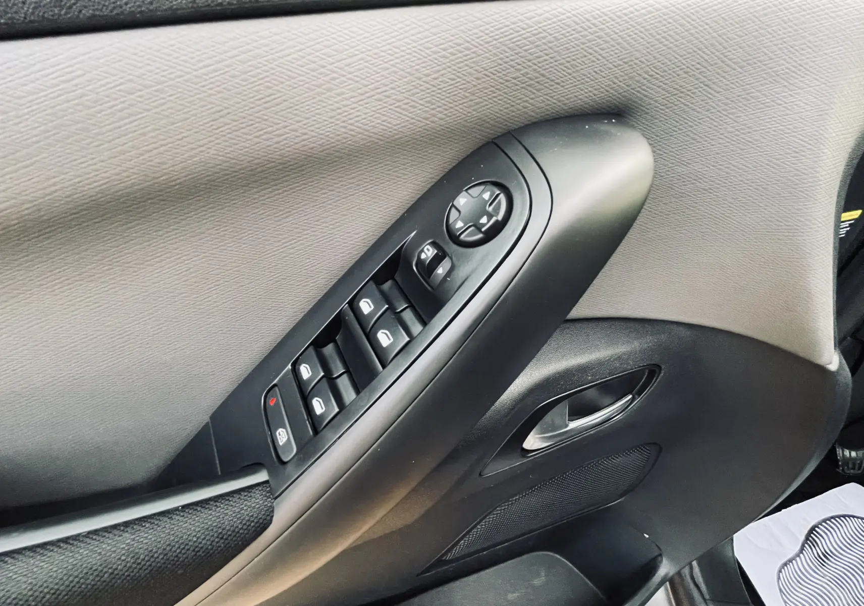 Panneau de porte côté gauche du Citroën C4 Picasso gris, avec commandes électriques des vitres et rétroviseurs.