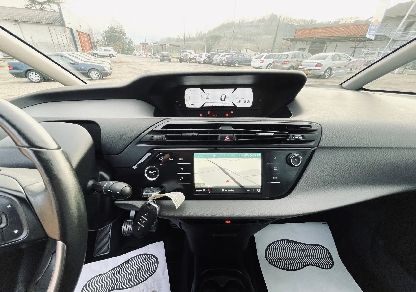Tableau de bord et console centrale du Citroën C4 Picasso gris, vue intérieure avant avec écran tactile et volant cuir.