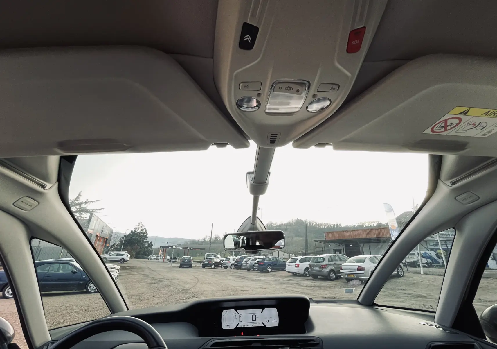 Vue intérieure avant du tableau de bord et du pare-brise panoramique d'une Citroën C4 Picasso gris clair.