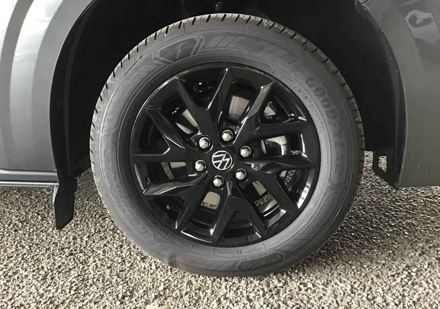 Gros plan sur la roue avant droite du Volkswagen Transporter gris anthracite avec jante noire brillante et pneu Goodyear.