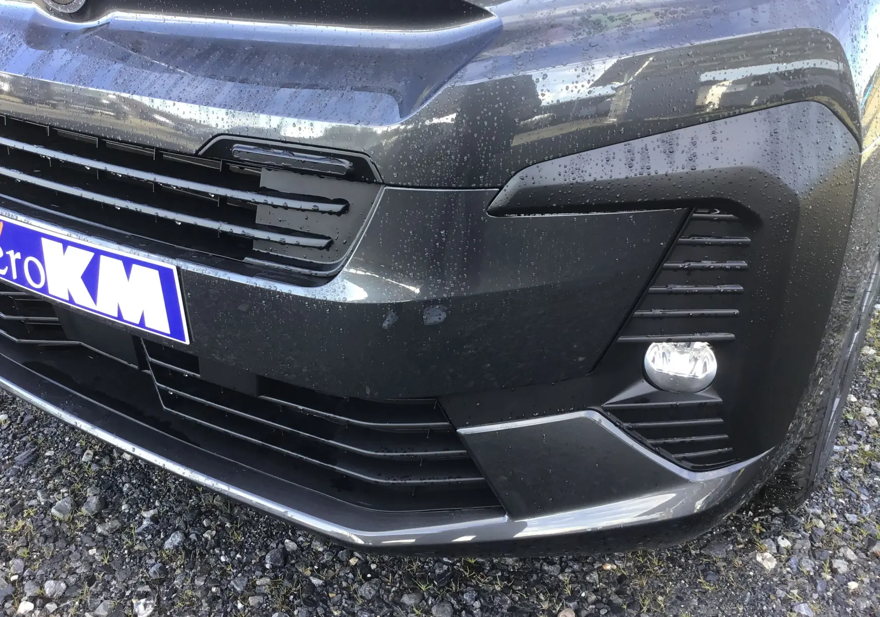 Gros plan sur l'avant droit gris titane du Citroën Jumpy Cabine Approfondie avec calandre et antibrouillard sous la pluie.