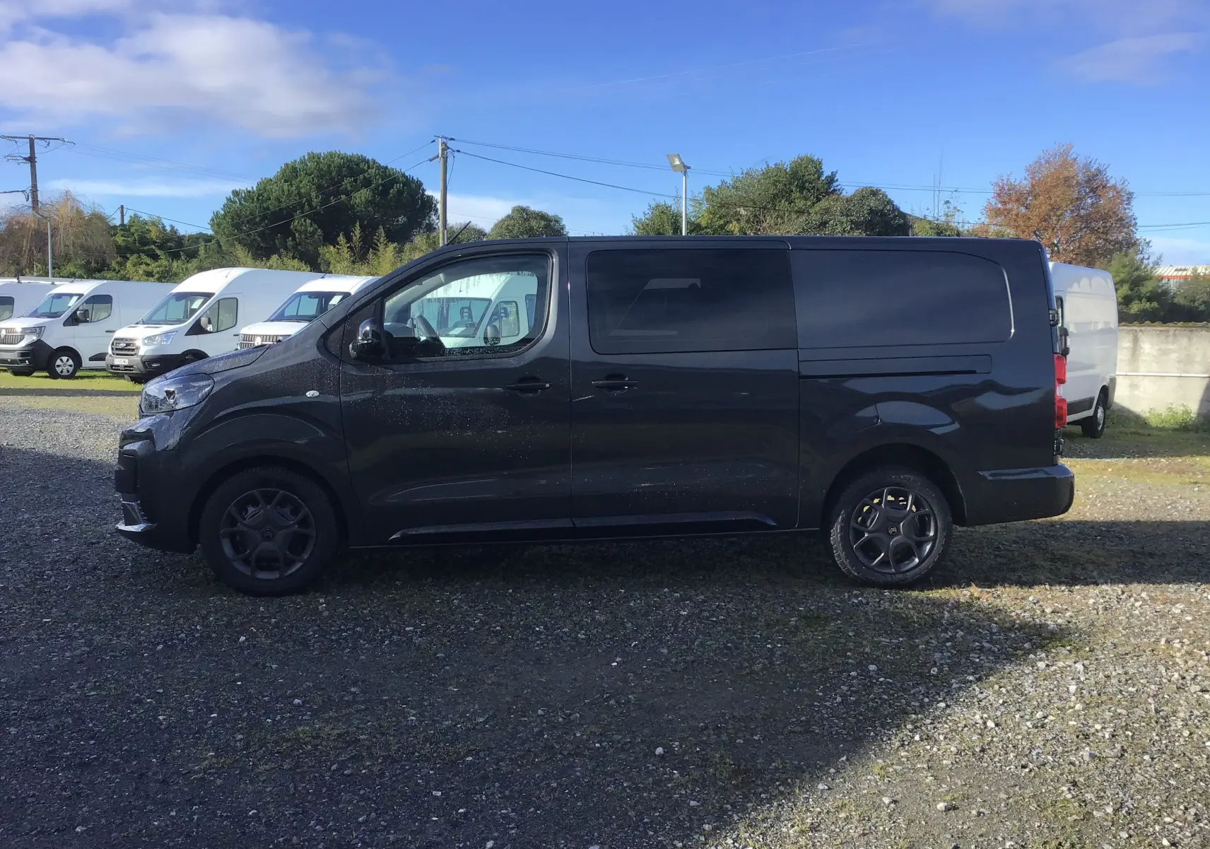 Profil côté gauche d'un Citroën Jumpy Cabine Approfondie gris titane, fourgon utilitaire avec jantes noires et vitres teintées.