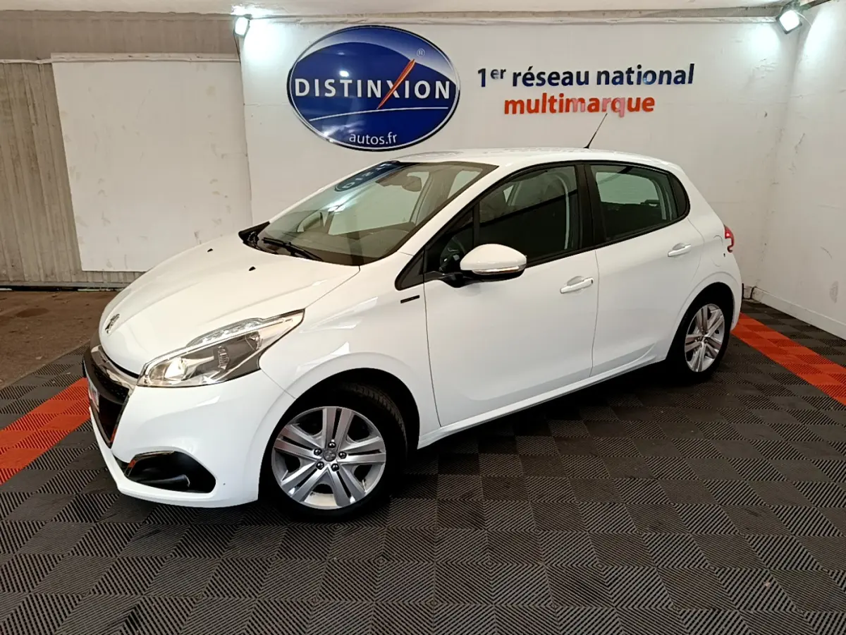 Peugeot 208 Puretech 82 Signature blanc vue 3/4 avant droit dans un showroom avec sol à damier noir et rouge.