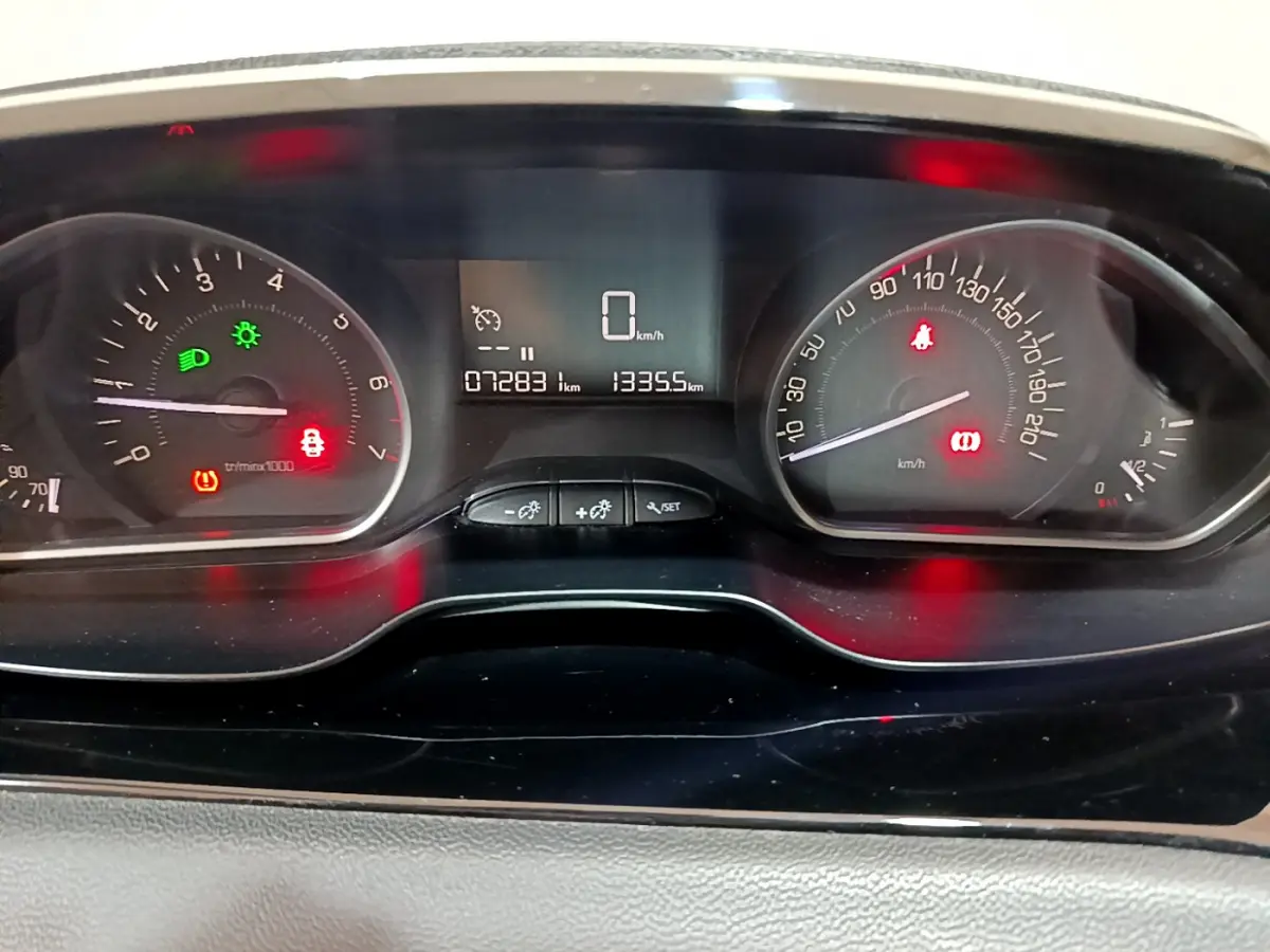 Tableau de bord de Peugeot 208 Puretech 82 Signature 2018, affichage numérique et compteurs analogiques allumés.