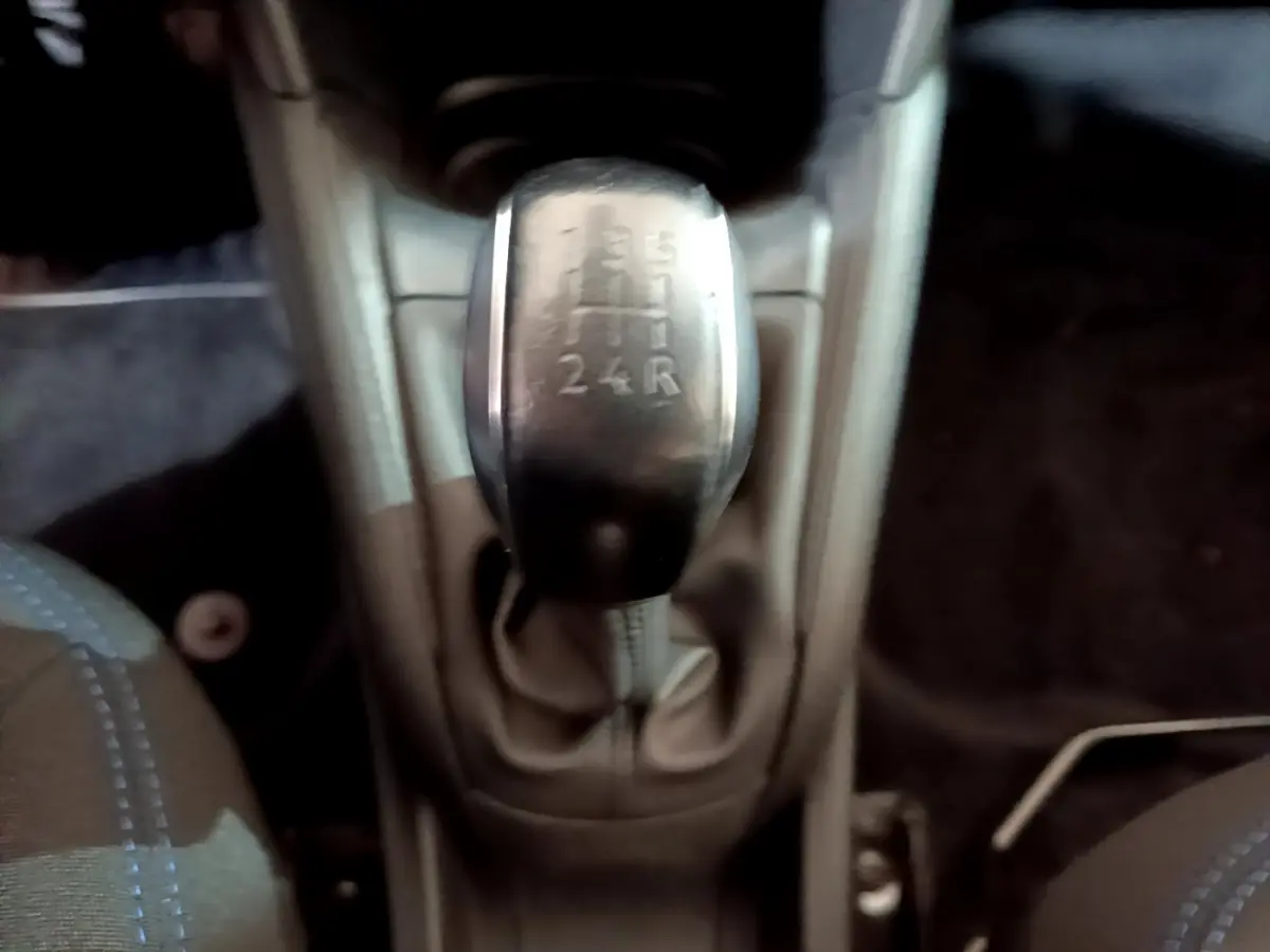 Le levier de vitesses manuel de la Peugeot 208 Puretech 82 Signature vu de dessus, intérieur sombre.