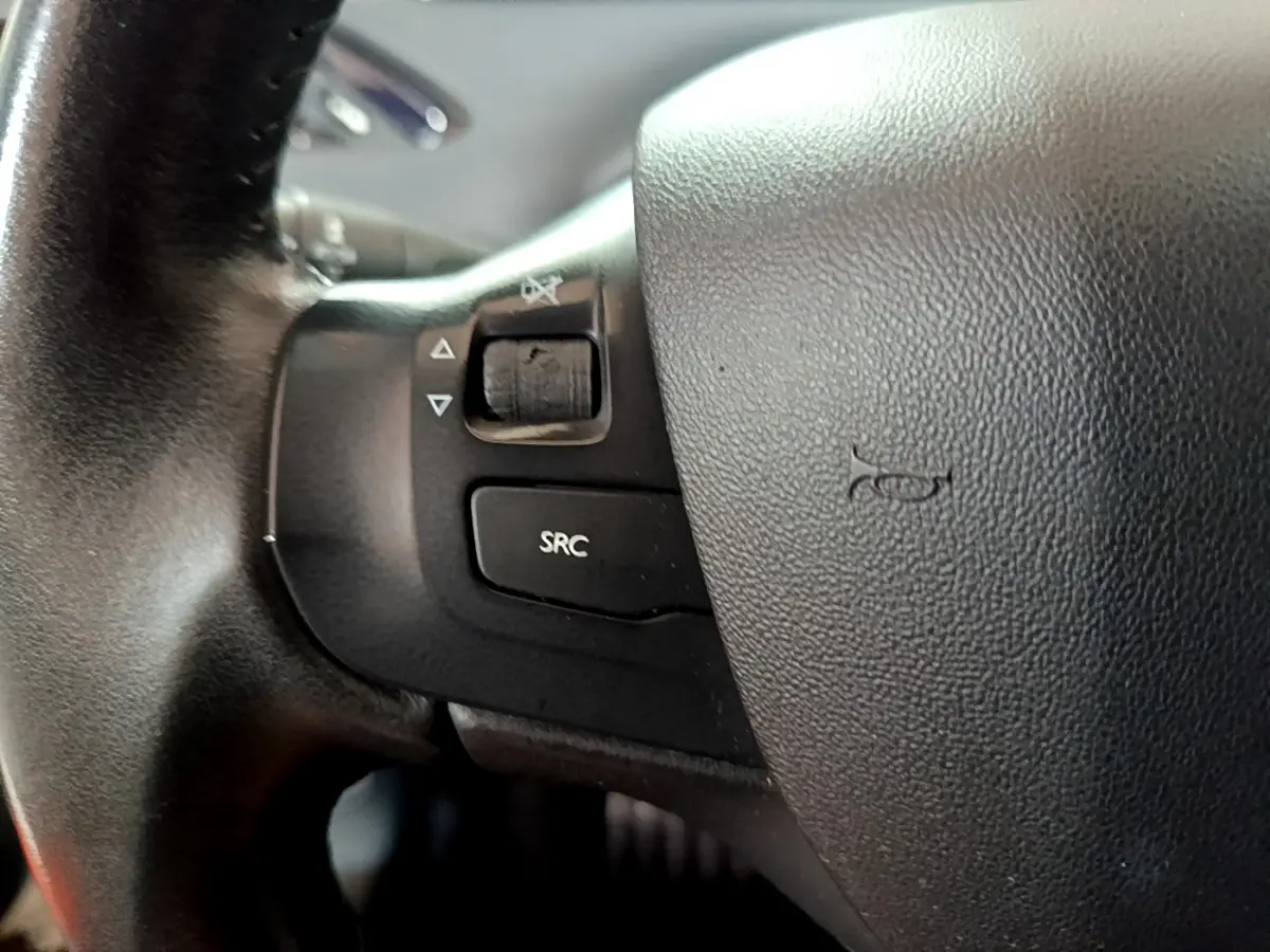 Gros plan sur les commandes gauche du volant cuir noir d'une Peugeot 208 Puretech 82 Signature blanche de 2018.