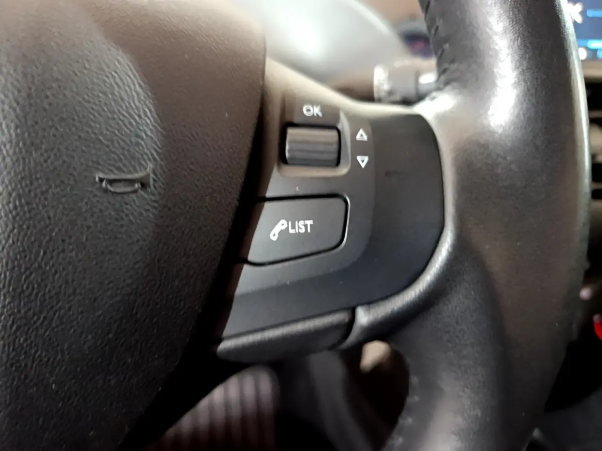 Gros plan sur les commandes gauche du volant cuir de la Peugeot 208 Puretech 82 Signature 2018.