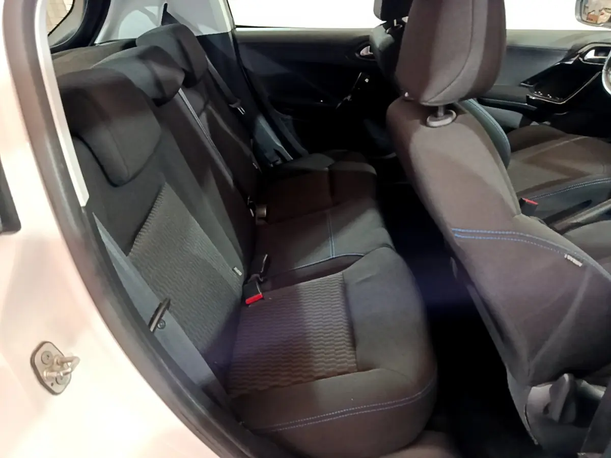 Vue intérieure côté gauche de la banquette arrière noire avec surpiqûres bleues d'une Peugeot 208 blanche Puretech 82 Signature 2018.