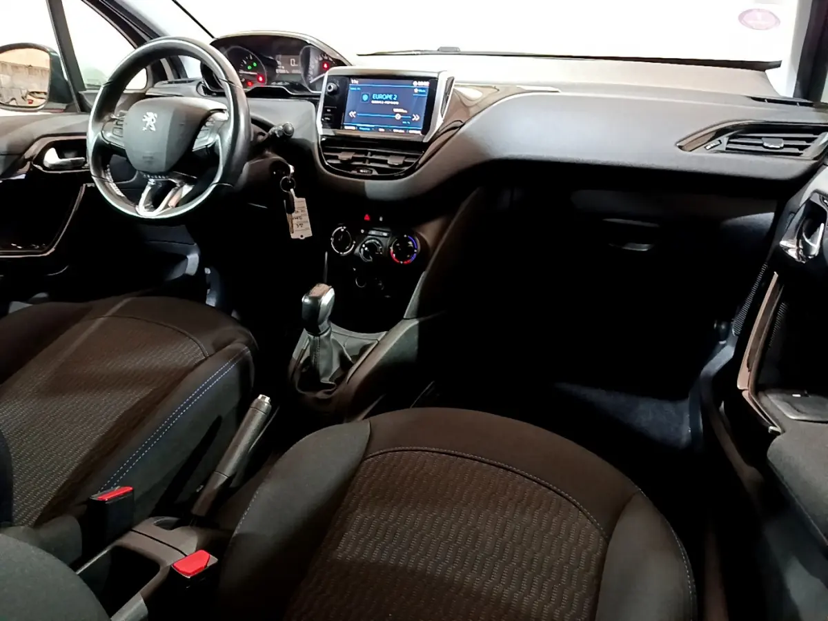 Intérieur de la Peugeot 208 Puretech 82 Signature 2018, vue côté conducteur, tableau de bord avec écran tactile et volant cuir.