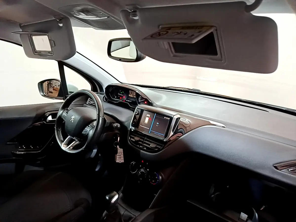 Intérieur de la Peugeot 208 Puretech 82 Signature 2018, vue côté conducteur, tableau de bord avec écran tactile et volant cuir.