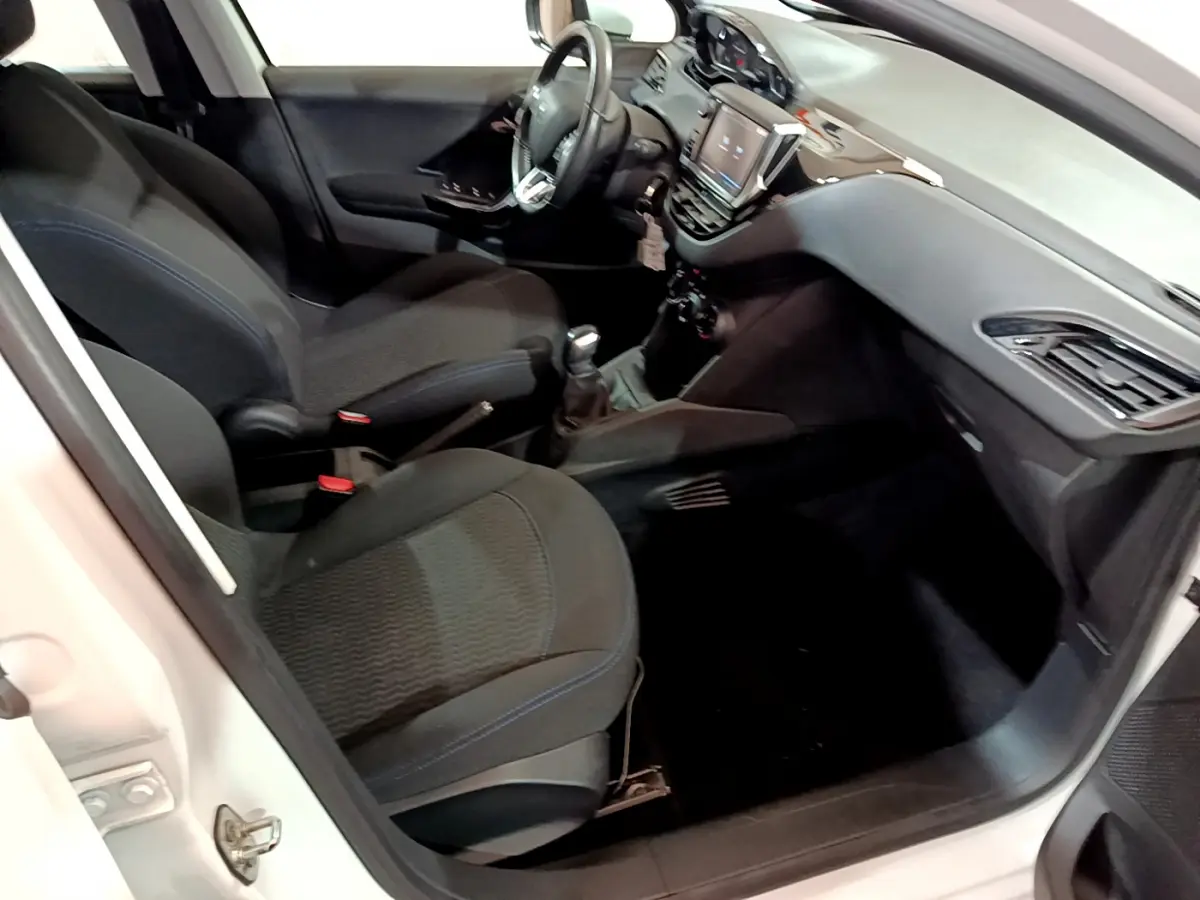 Intérieur de la Peugeot 208 Puretech 82 Signature 2018, vue côté droit, sièges noirs et tableau de bord moderne.