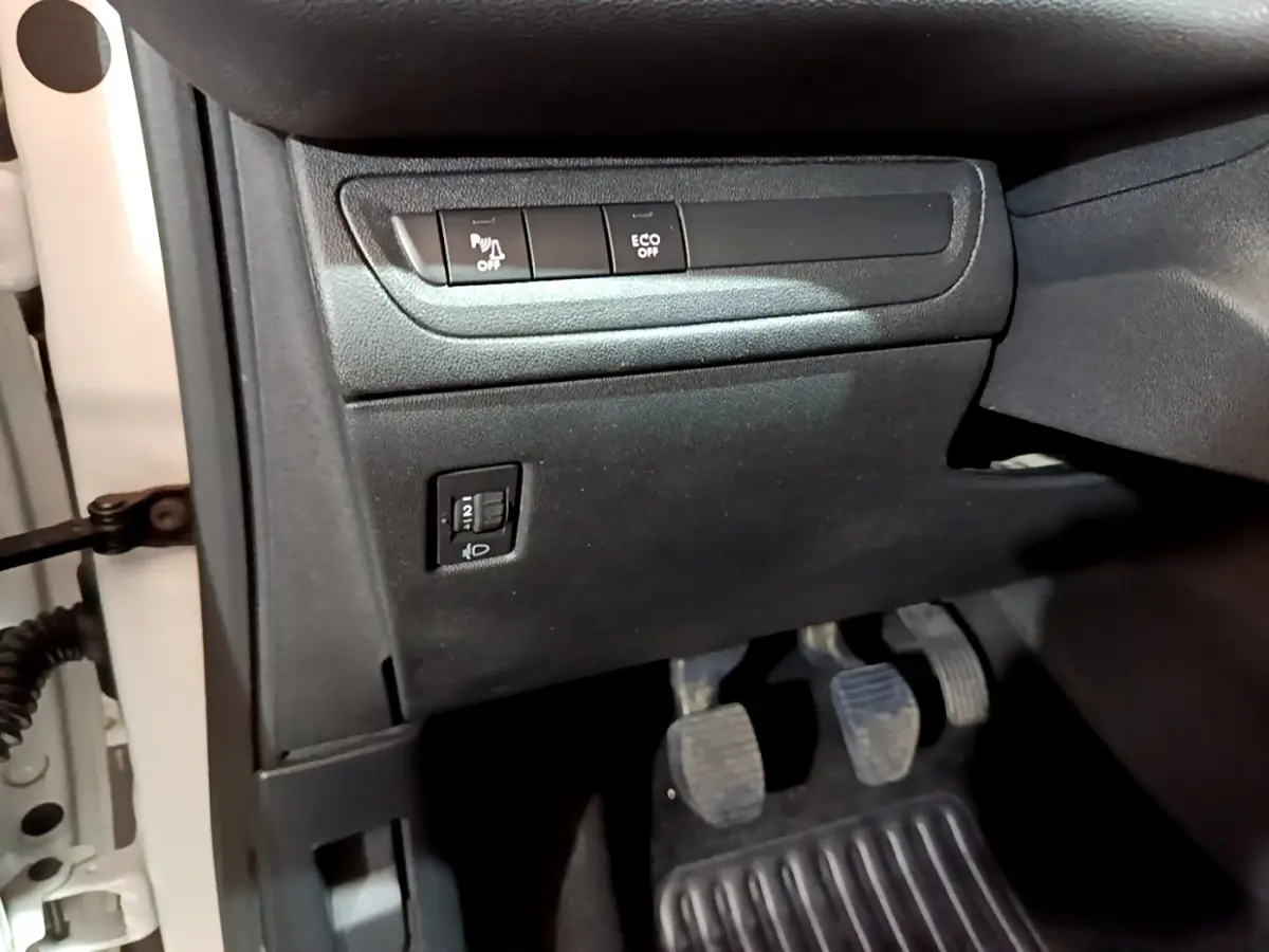 Vue du tableau de bord côté gauche avec commandes de régulation phares et désactivation capteurs sur Peugeot 208 blanc