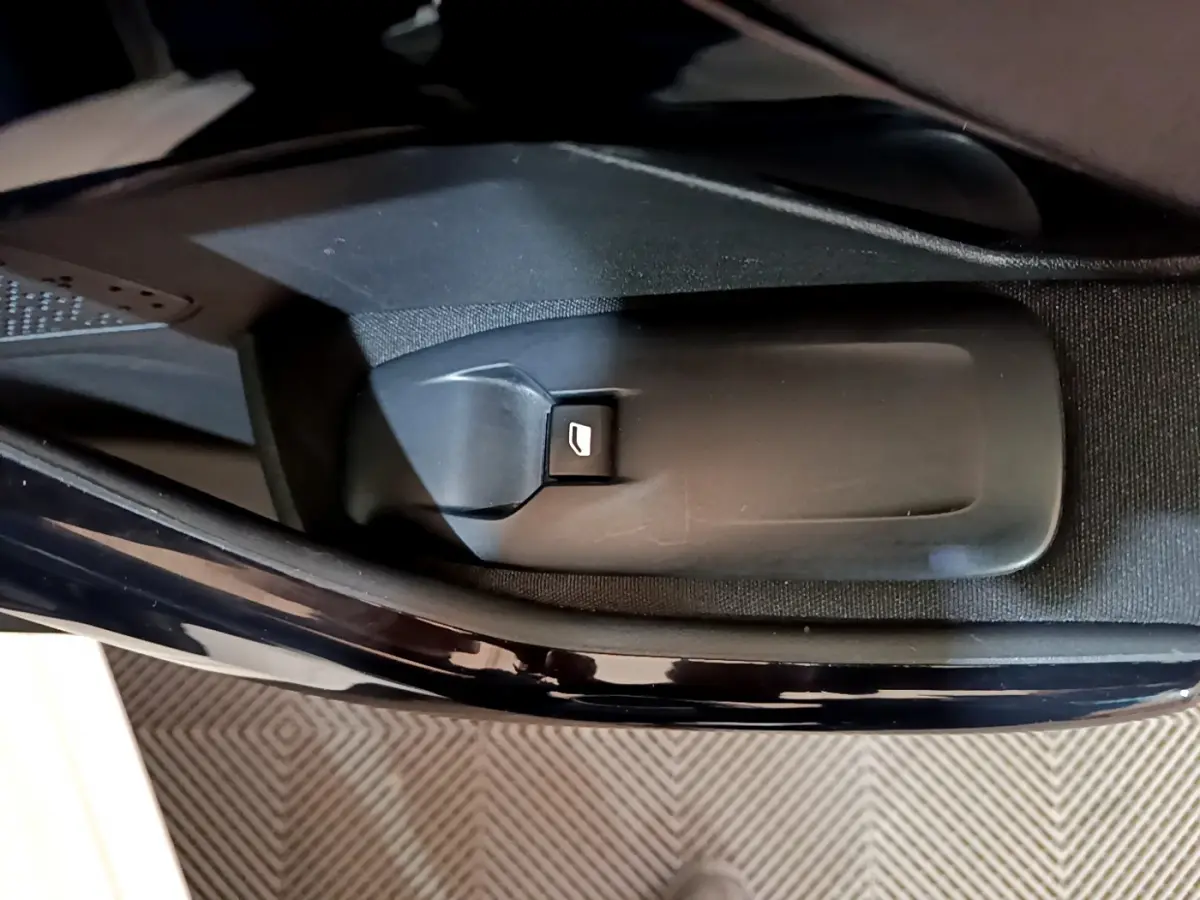 Gros plan sur le bouton d'ouverture de coffre côté conducteur de la Peugeot 208 Puretech 82 Signature blanche.