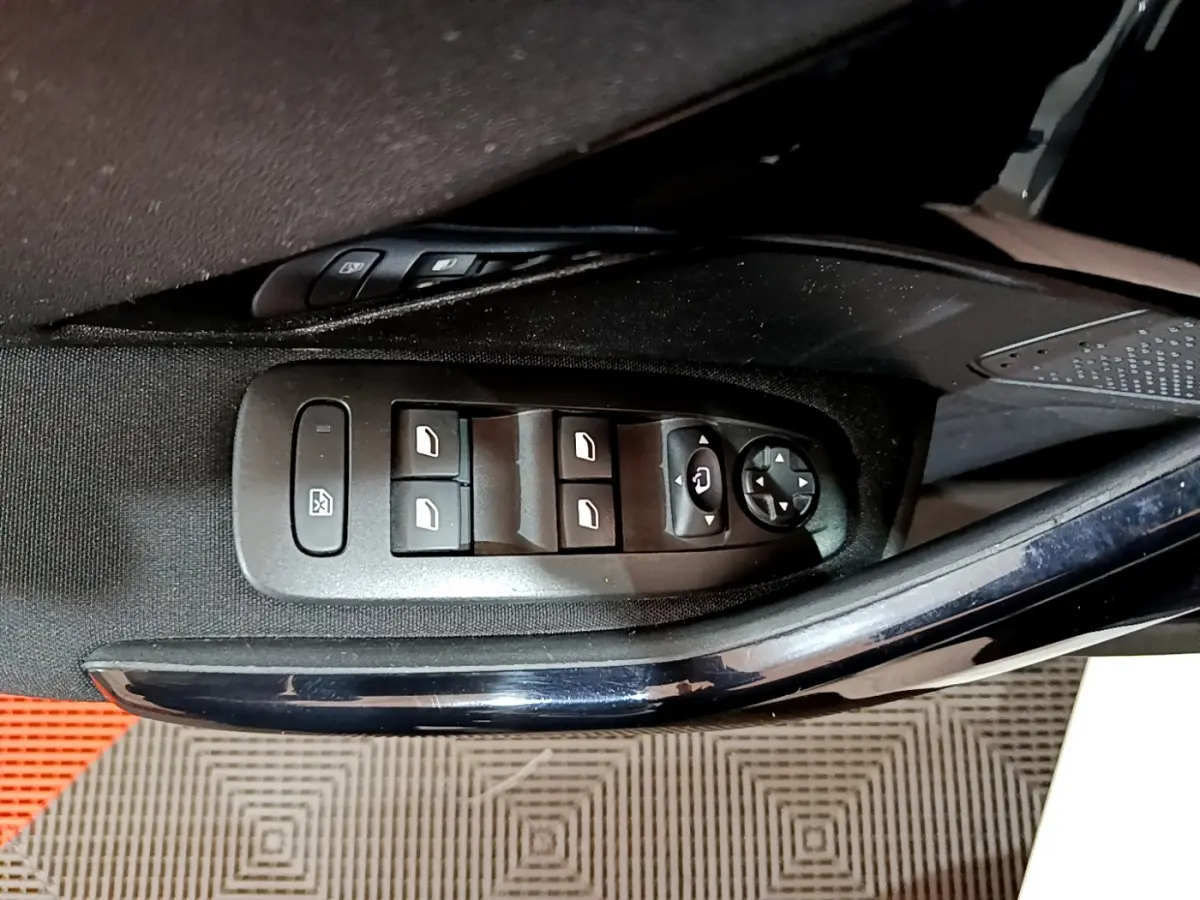 Gros plan sur les commandes des vitres électriques et rétroviseurs côté gauche d'une Peugeot 208 blanche.