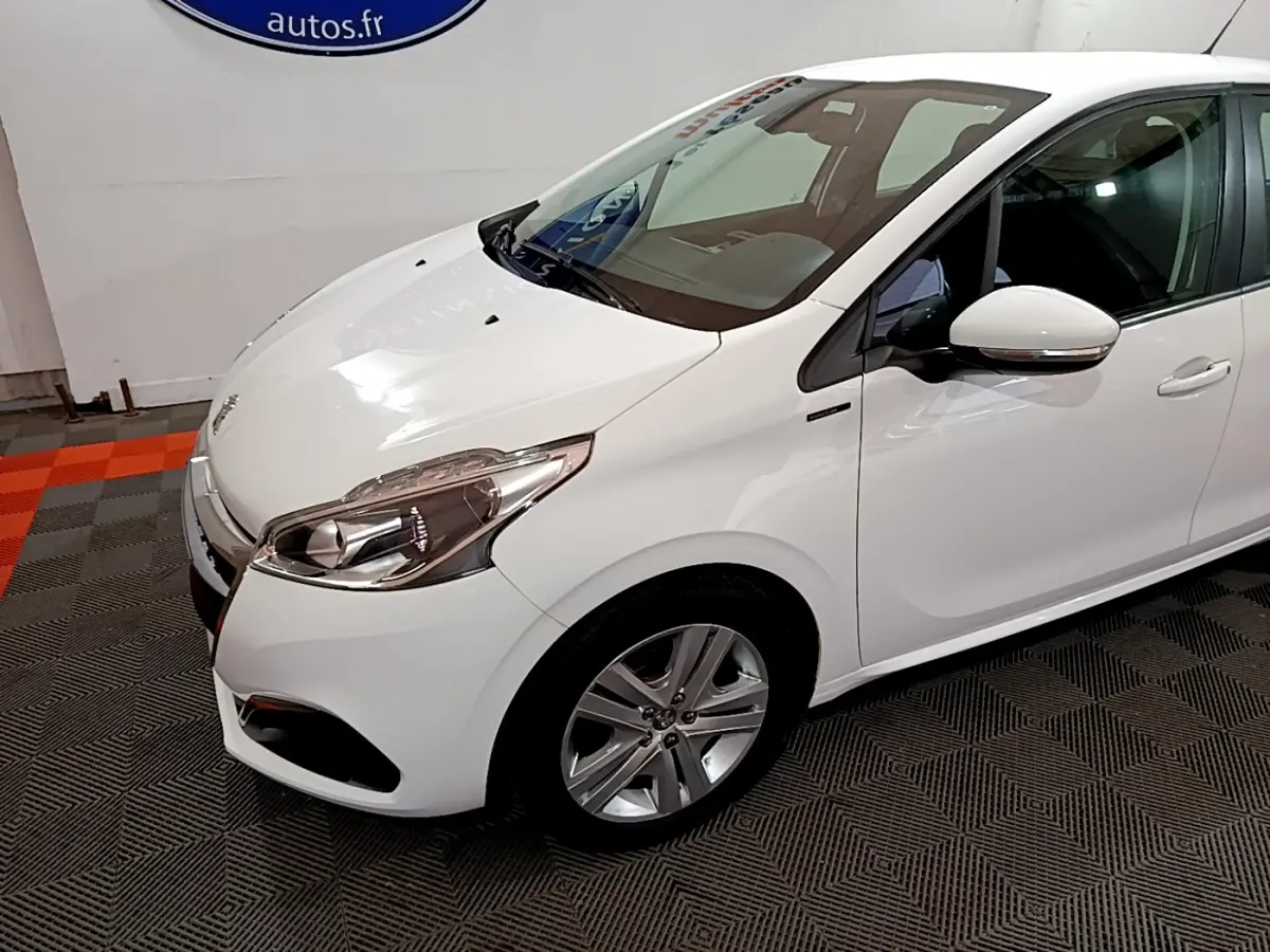 Peugeot 208 Puretech 82 Signature blanc vue 3/4 avant droit, avec phares LED et jantes alliage visibles.