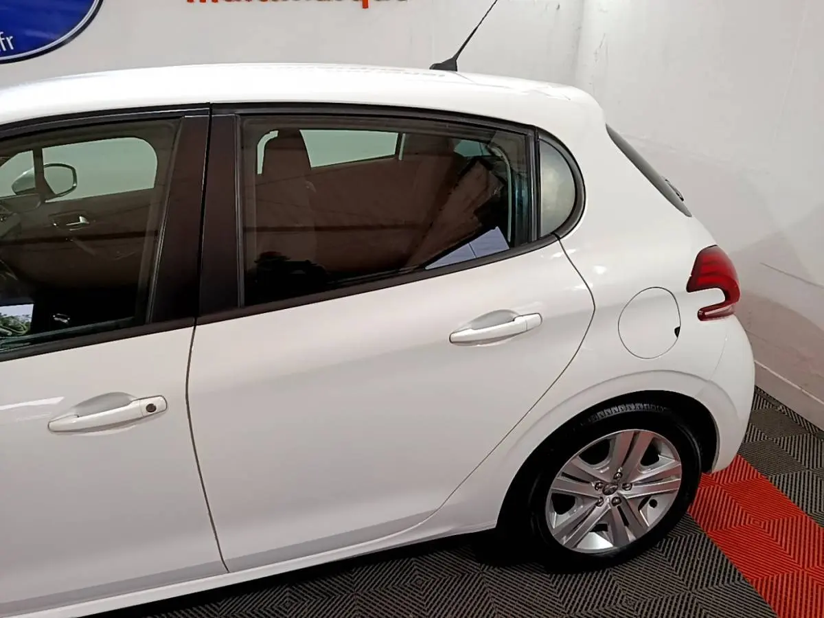 Vue latérale droite d'une Peugeot 208 blanche, mettant en valeur la porte arrière et la roue arrière en alliage.