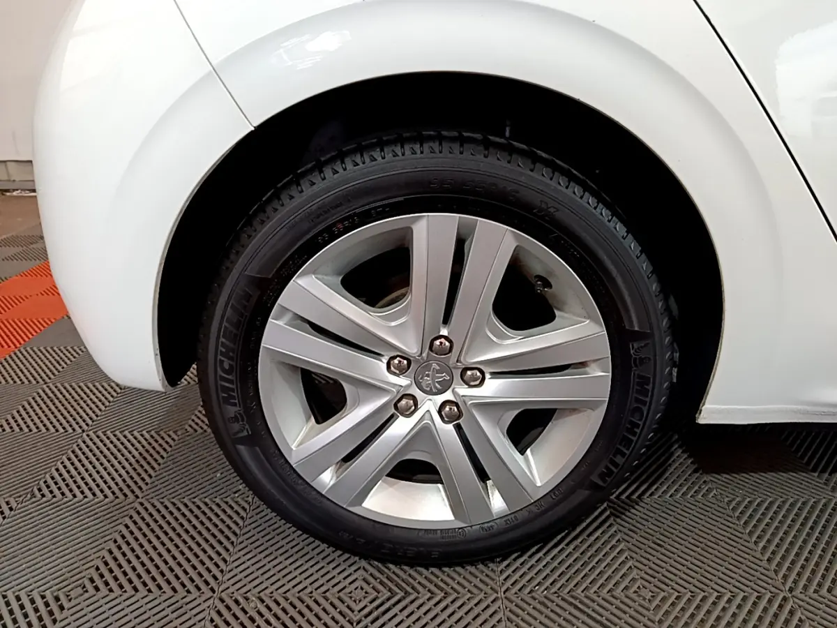 Gros plan sur la roue avant droite blanche d'une Peugeot 208 Puretech 82 Signature avec jante alliage et pneu Michelin.