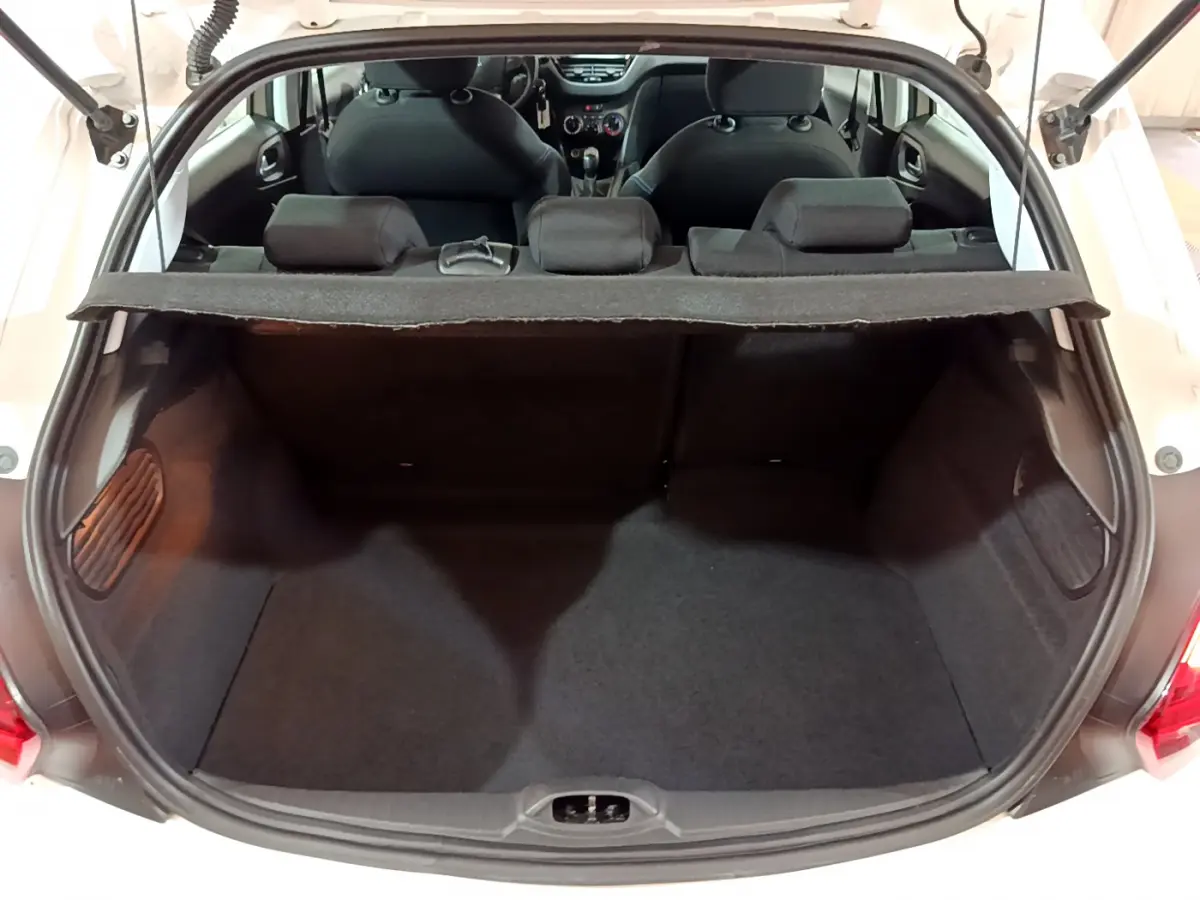 Coffre ouvert vu de l'arrière d'une Peugeot 208 blanche, montrant l'espace de chargement et les sièges arrière.