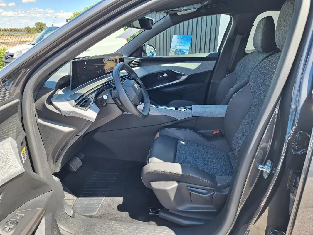 Vue intérieure côté conducteur du Peugeot 3008 Hybrid 136 gris foncé, avec sièges bi-matière et cockpit numérique.