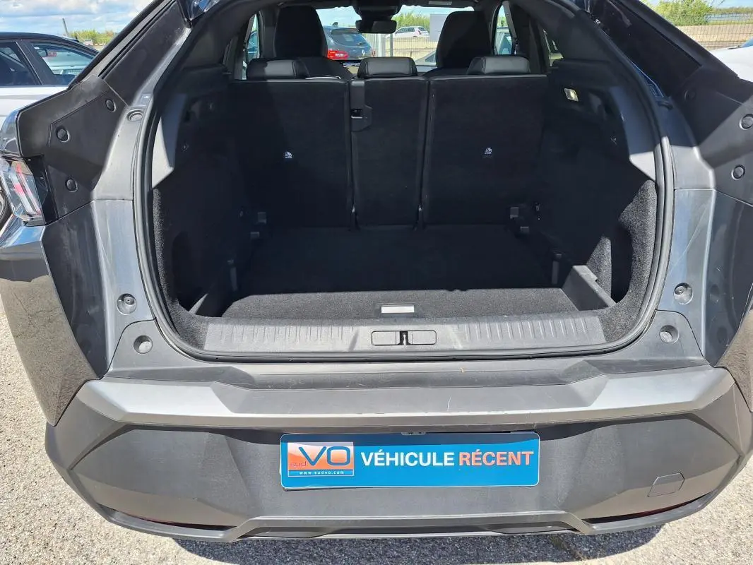 Coffre ouvert vu de l’arrière d’un Peugeot 3008 gris foncé, montrant l’espace de chargement vide et les sièges arrière.