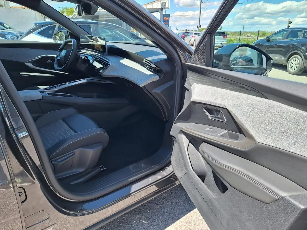 Intérieur côté passager du Peugeot 3008 Hybrid gris foncé 2025, avec tableau de bord moderne et sellerie bicolore.