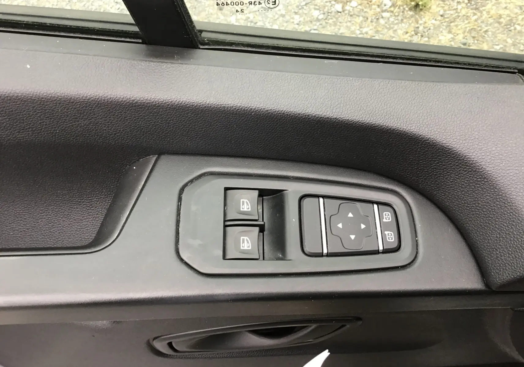 Gros plan sur les commandes de lève-vitres et réglage des rétroviseurs côté conducteur du Renault Trafic Fourgon blanc 2024.