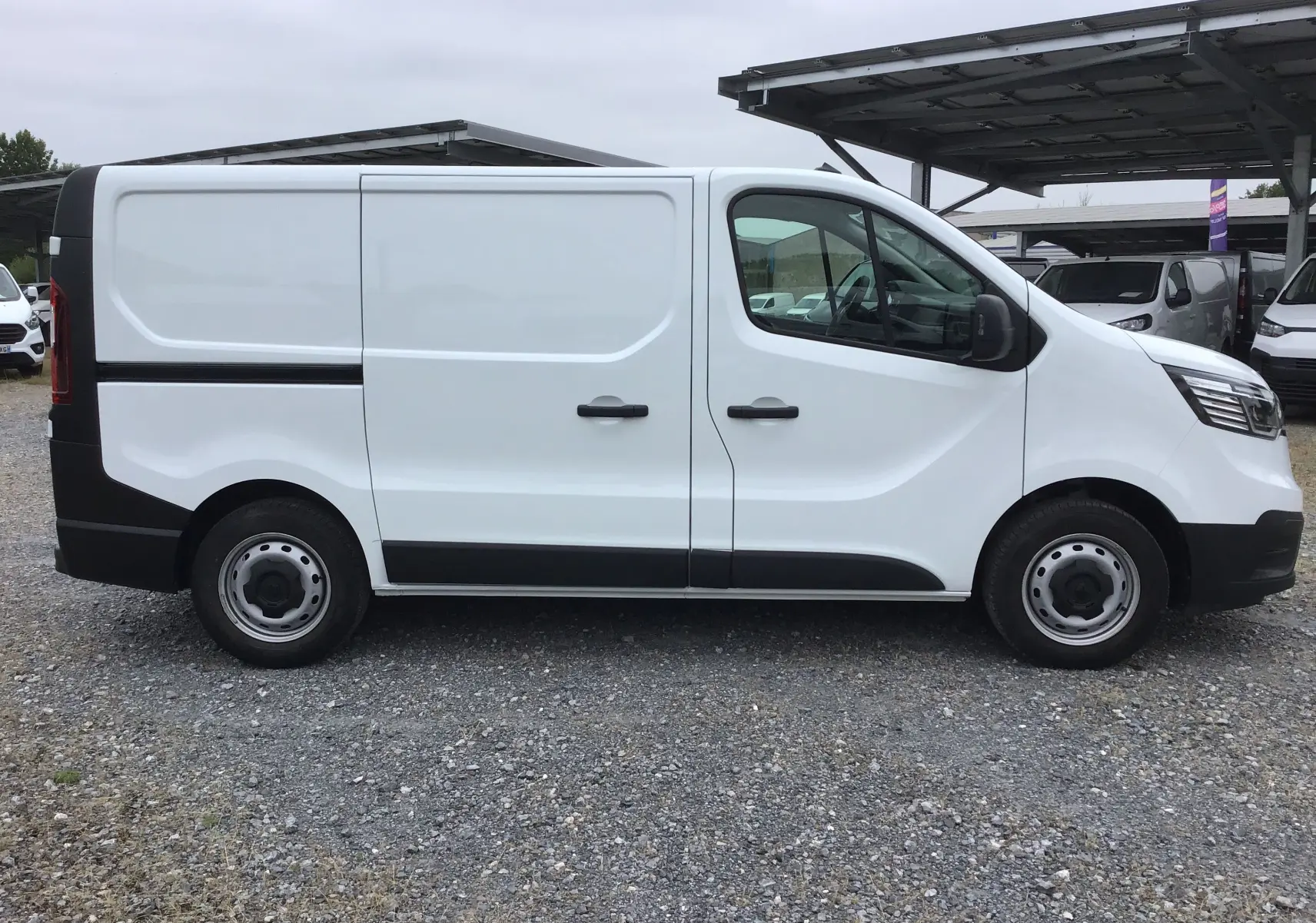 Vue de profil côté gauche d’un Renault Trafic Fourgon blanc 2024 avec portes latérales et jantes acier.