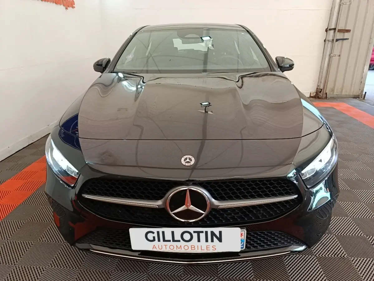 Vue avant d'une Mercedes Classe A 250 e Business Line noire avec calandre étoile et phares LED allumés.