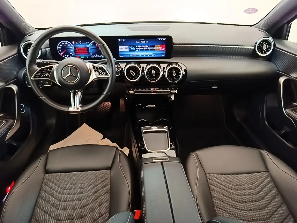 Vue intérieure avant de la Mercedes Classe A 250 e Business Line 2023, tableau de bord noir avec écran tactile et volant cuir.